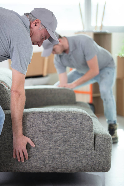 professional men moving a sofa into a property - Fotoğraf, Görsel