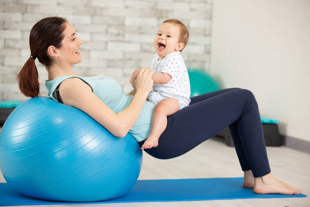 mother is engaged in fitness as she exercises with baby - Photo, Image