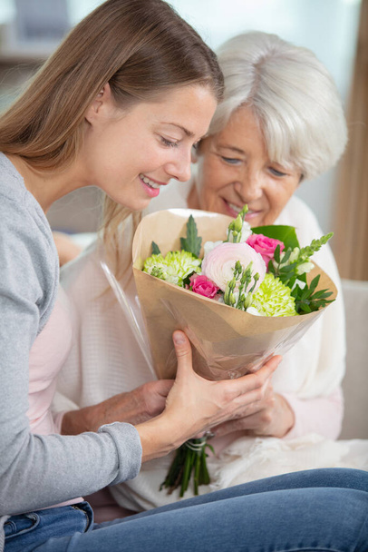 portrait of happy grandma with flowers at home - Fotografie, Obrázek