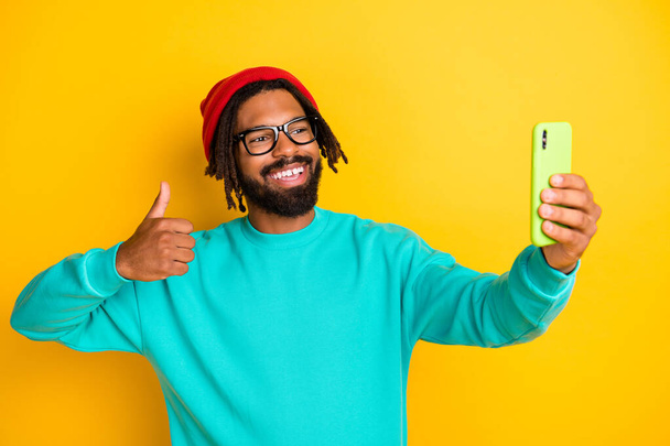 Photo of young african man happy positive smile show thumb-up make selfie cellphone isolated over yellow color background - Foto, imagen