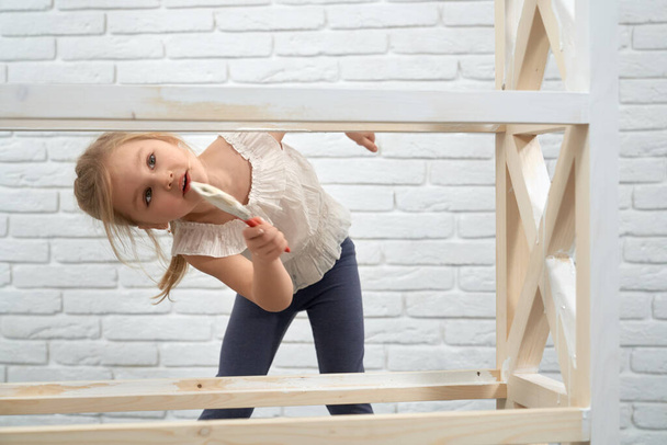 Child painting wooden rack in white color. - Photo, Image