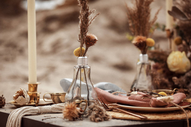 A table  designed for a boho style event with an eucalyptus, vintage plates and other rustic touches. On seaside in the sand - Фото, зображення