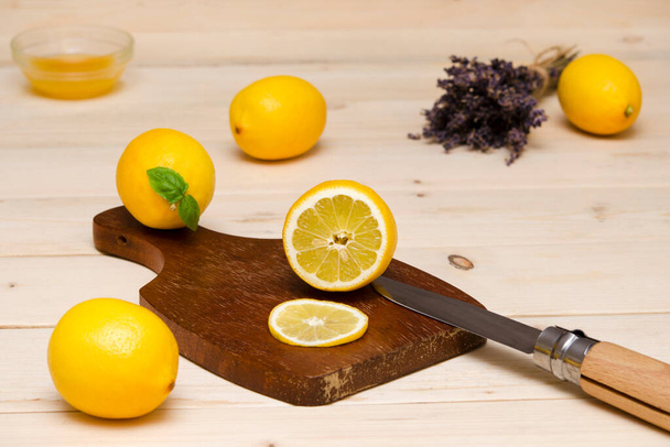 limones enteros y cortados en una tabla de cortar y un cuchillo - Foto, imagen