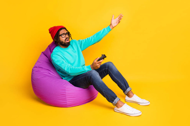 Full size profile photo of brunette sad guy playstation wear cap spectacles pullover jeans isolated on yellow background - Foto, Imagen