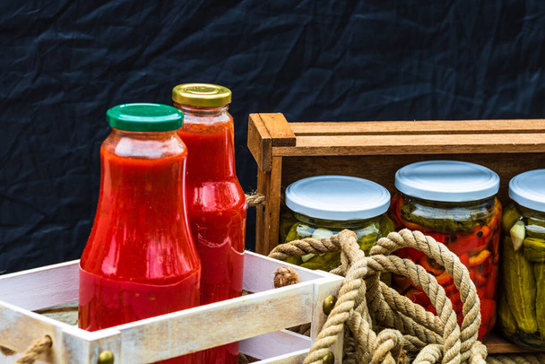 Flessen tomatensaus, verduurzaamd ingeblikt voedselconcept geïsoleerd in een rustieke samenstelling. - Foto, afbeelding
