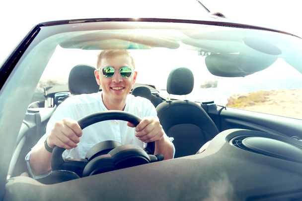 onnellinen nuori mies ajaa autoa rannalla - Valokuva, kuva
