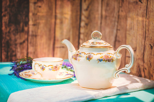 Kilátás egy csésze tea és egy finom porcelán teáskanna az asztalon naplementekor - Fotó, kép