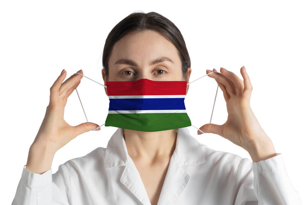 Respirator with flag of Gambia Doctor puts on medical face mask isolated on white background. - Photo, Image