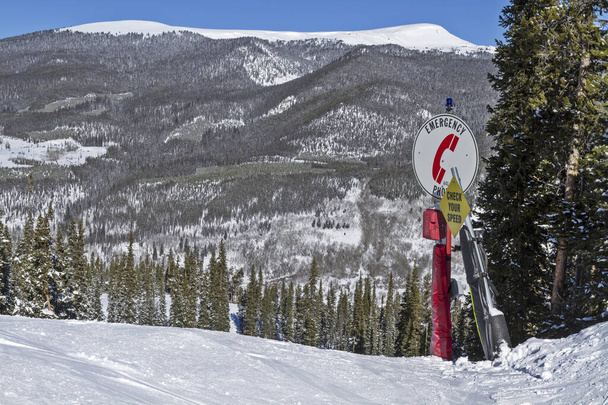 Dağ kayak merkezinin yamacında acil durum telefonu işareti. Parlak kırmızı, arka planda dağ var. Colorado 'da kış. - Fotoğraf, Görsel