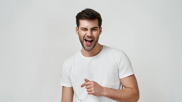 Happy bearded young man in white t-shirt winking - Photo, Image