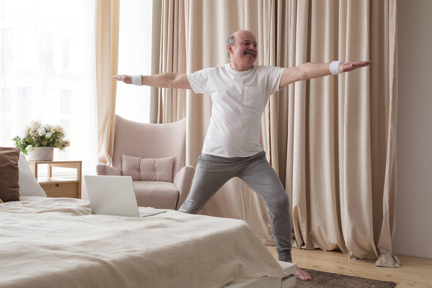Oudere man beoefent yoga of fitness. Positieve stemming over sportactiviteiten - Foto, afbeelding