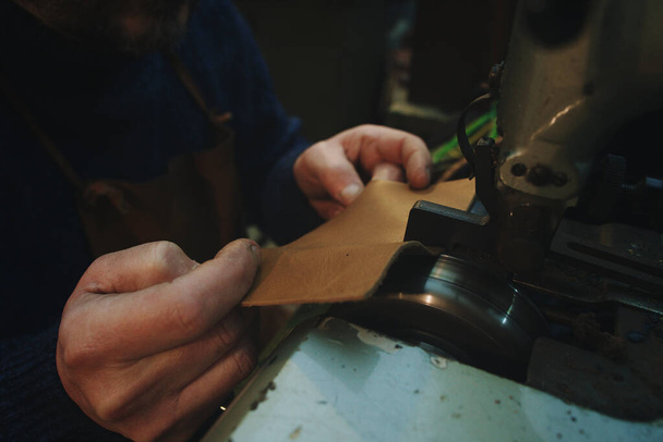 hands of craftsman work leather with thinning machinery - Φωτογραφία, εικόνα