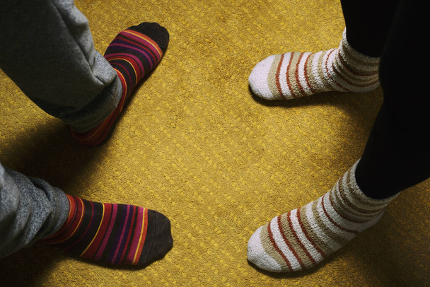 pies de mujer y hombre con calcetines de colores en la alfombra amarilla. amor en la casa - Foto, imagen