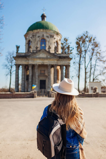 Турист смотрит на древнюю римско-католическую церковь святого Иосифа в Подгорцах, Украина. Посещение памятников древней архитектуры и исторических мест - Фото, изображение