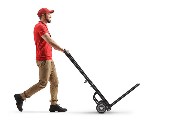 Delivery man pushing an empty hand truck isolated on white background - Fotó, kép