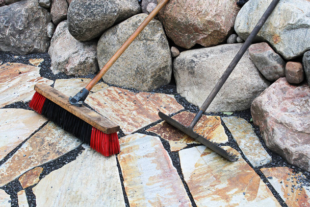Грабли и метла, используемые на камнях патио - Фото, изображение