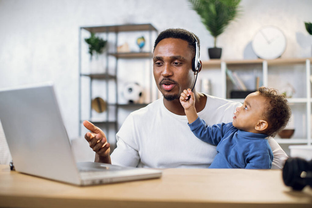 African man having video chat on laptop with baby on hands - Φωτογραφία, εικόνα