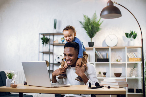 African father with cute son on neck working on laptop - Zdjęcie, obraz