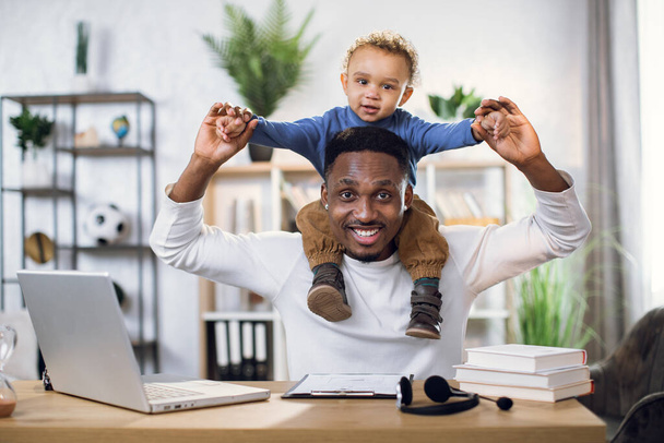Afro american father with son on neck working from home - Foto, immagini