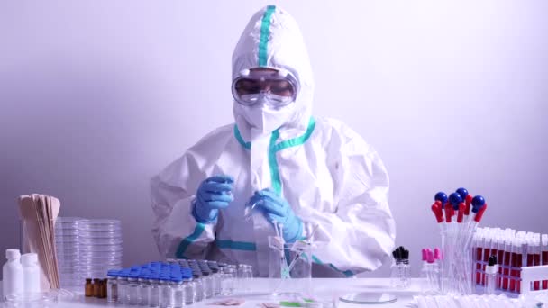 Doctor or nurse in full ppe suit preparing syringe with Covid 19 vaccine. Vaccination against coronavirus in the hub. Equipped laboratory with many vaccine vials and tools. - Filmmaterial, Video
