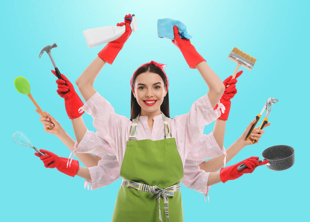 Multitask housewife with many hands holding different stuff on blue background - Photo, image
