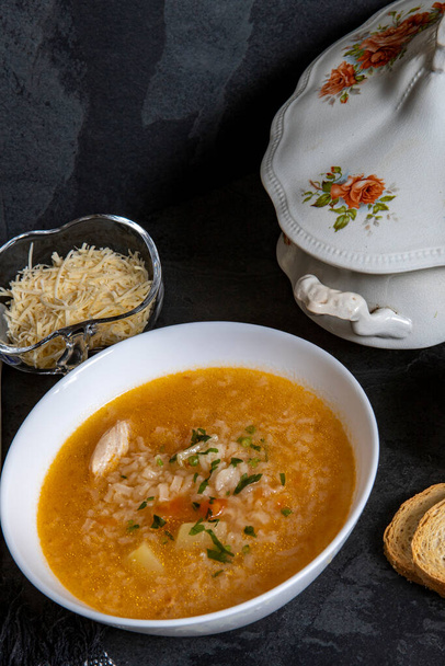 Бразильская кухня - Куриный суп или Canja de galinha в Португалии - традиционные блюда Бразилии, суп с курицей и рисом подается на украшенной антикварной миске супа XIX века - Фото, изображение