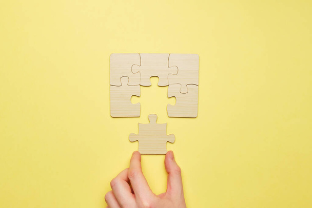 Person assembles a wooden puzzle and connects the last piece. - Photo, Image