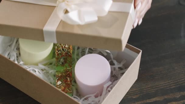 Widok góry żeńskich rąk wiążących wstążki w kokardkę na pięknym pudełku z ręcznie robionymi kosmetykami z naturalnych składników organicznych - Materiał filmowy, wideo