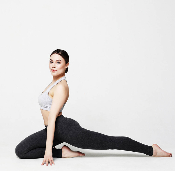 Young woman practicing yoga, working out, wearing sportswear, studio shoot over white background - Fotografie, Obrázek