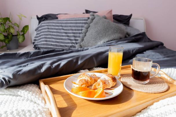 Healthy breakfast tray and freshly squeezed orange juice are on bed in the bedroom. Healthy food concept. The room is bathed in sunlight. - Fotoğraf, Görsel
