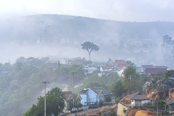 Pieni kaupunki teekukkulan laakson alla aamulla. Sumu peittää sen Da Latissa, Vietnamissa. Paikka tarjoaa paljon teetä koko maalle. - Valokuva, kuva