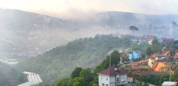 Małe miasteczko pod doliną wzgórza herbacianego rano z mgłą pokrywającą wzgórza Da Lat w Wietnamie. To miejsce dostarcza dużo herbaty dla całego kraju. - Zdjęcie, obraz