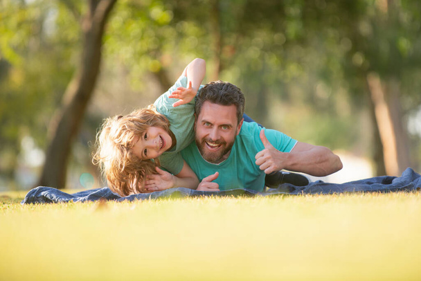 Father and son relaxing on nature in park. Happy dad and child boy enjoying summer time on vacation in a sunny park. - 写真・画像