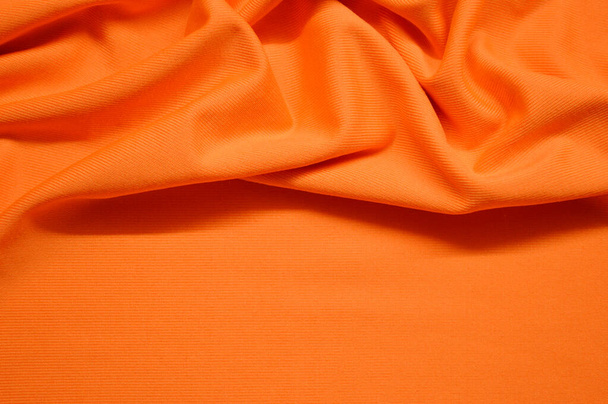 Arka plan olarak turuncu tekstil deseni. Kumaşın turuncu dokusunu kapat. Buruşmuş kumaş dokusu - Fotoğraf, Görsel