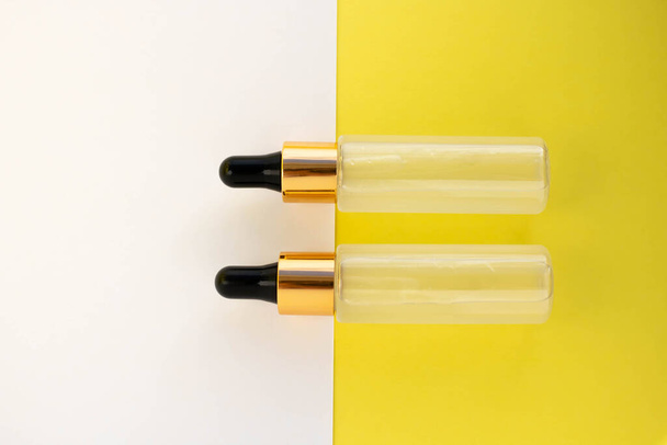 Deux bouteilles de gel transparent liquide cosmétique sur fond jaune blanc. Style de style plat. - Photo, image