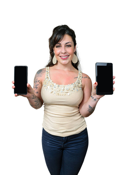 Бразильская женщина улыбается, татуируется, держит и показывает на камеру смартфон и планшет. белый фон. - Фото, изображение