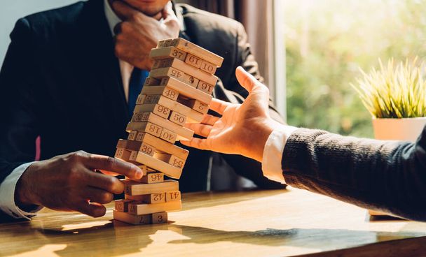 Business man strategy risk pulling block wood tower and have one businessman help to support - Photo, Image