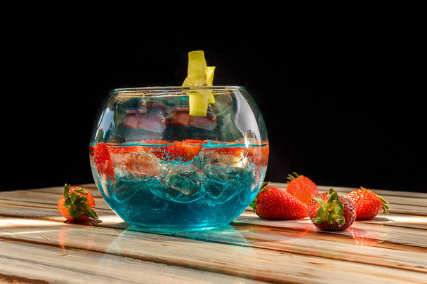 Close-up of a blue drink with strawberries served in a glass fishbowl - Foto, immagini