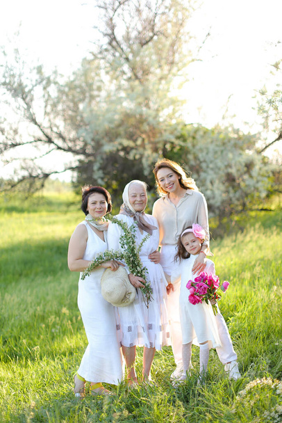 Caucásico abuelita en vestido blanco con hija y nietas al aire libre. - Foto, imagen