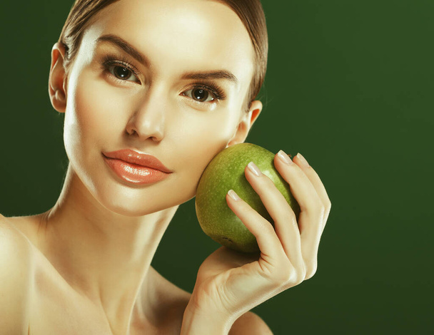 Young woman with green apple over green background - 写真・画像
