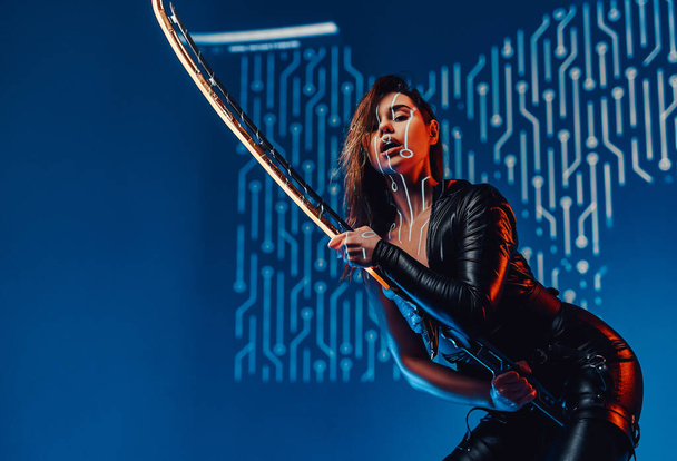 Sensual cyberpunk woman assassin posing with sword - Foto, Imagen