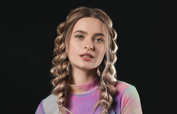 Красивая молодая женщина с плетеными волосами на темном фоне - Фото, изображение