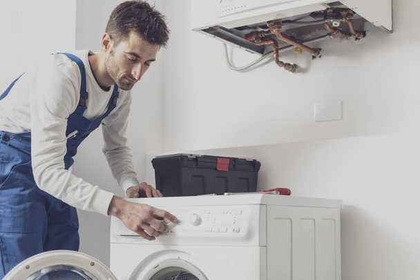 Repairman fixing a washing machine, he is adjusting a knob, professional service concept - Foto, Bild