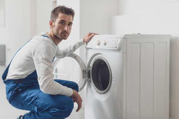 Professional repairman checking a washing machine, he is looking at camera - Fotoğraf, Görsel