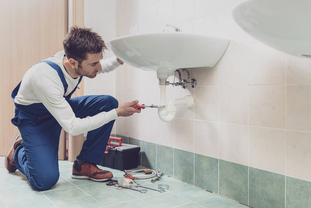 Professional plumber installing or fixing a sink at home - Foto, immagini