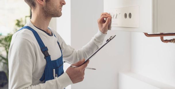Professional plumber checking a boiler control panel, he is adjusting a knob - Photo, Image