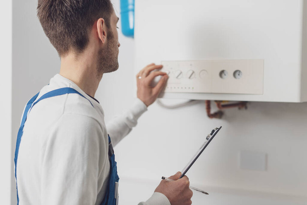 Professional plumber checking a boiler control panel, he is adjusting a knob - Foto, imagen