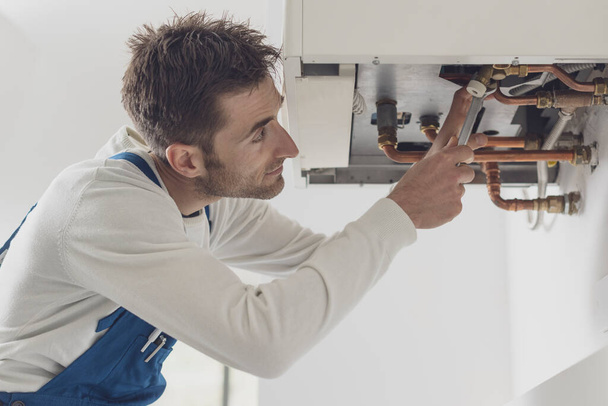 Professional plumber checking a boiler and pipes, boiler service concept - Zdjęcie, obraz