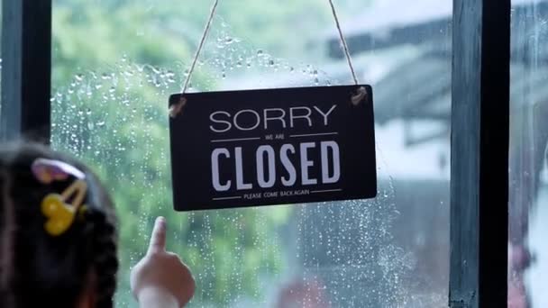 Een open bord hangend aan de voordeur van het restaurant zwaaiend op een regenachtige dag. - Video