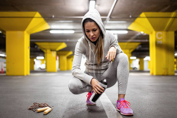 Young woman training in garage while listening to music. Fitness, sport, people and healthy lifestyle concept. - Valokuva, kuva